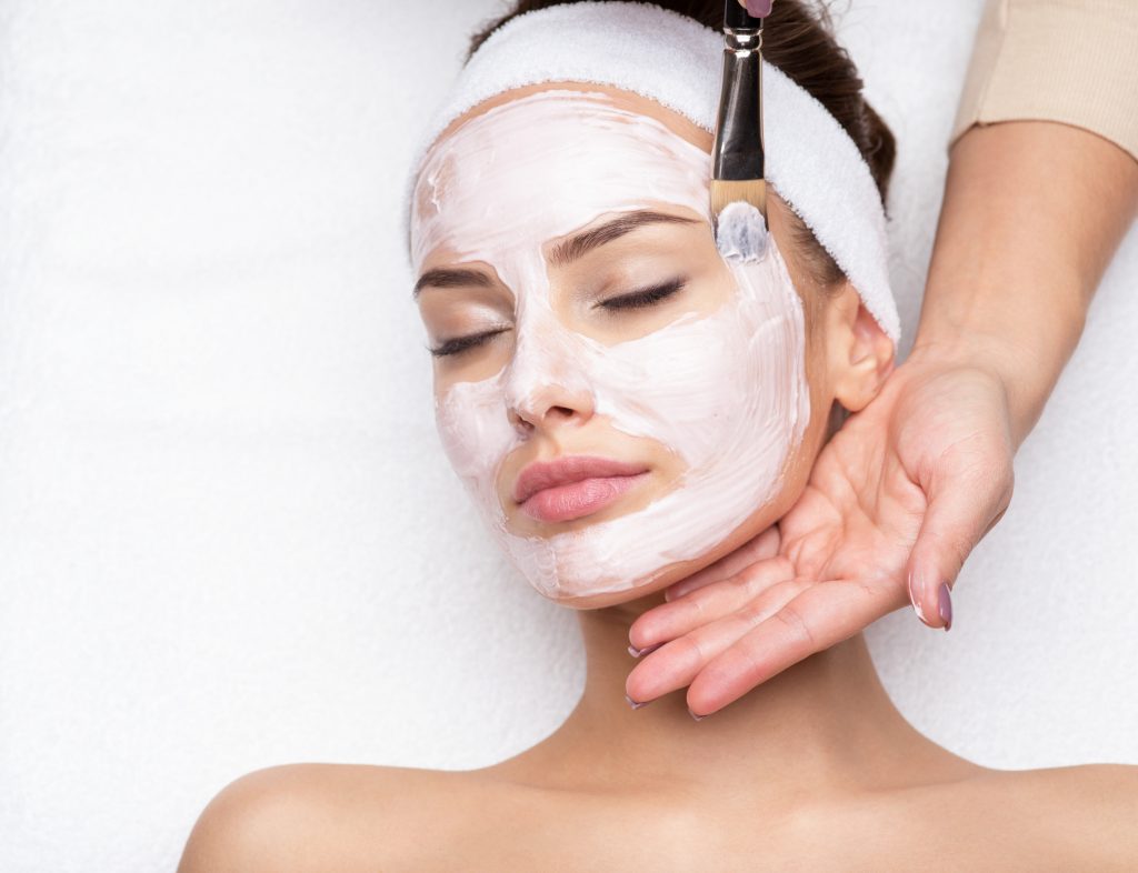 Red Carpet Facial Woman receiving facial mask at beauty salon